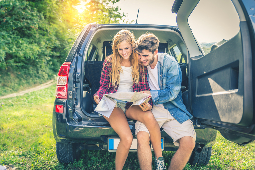 Young,Happy,Couple,Sitting,On,Car,Looking,At,Map,- Insurance Massachusetts